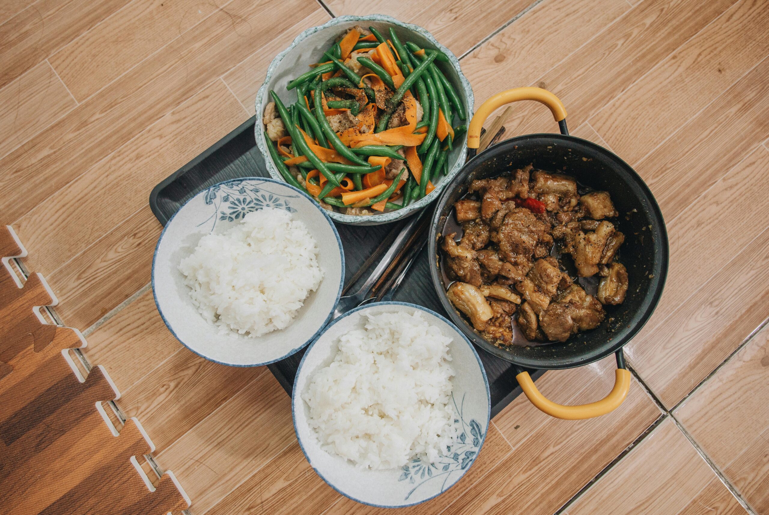 Close-up of a tasty Asian meal featuring pork, vegetables, and rice, beautifully arranged.