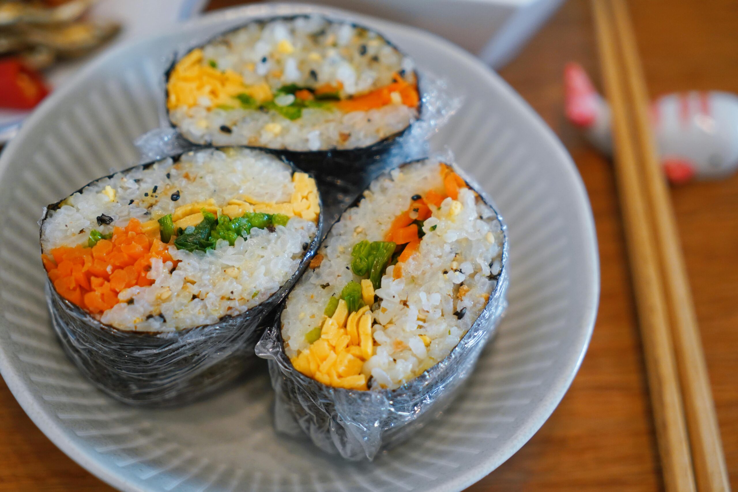 Close-up of homemade sushi filled with carrots, egg, and greens on a plate, perfect for food enthusiasts.